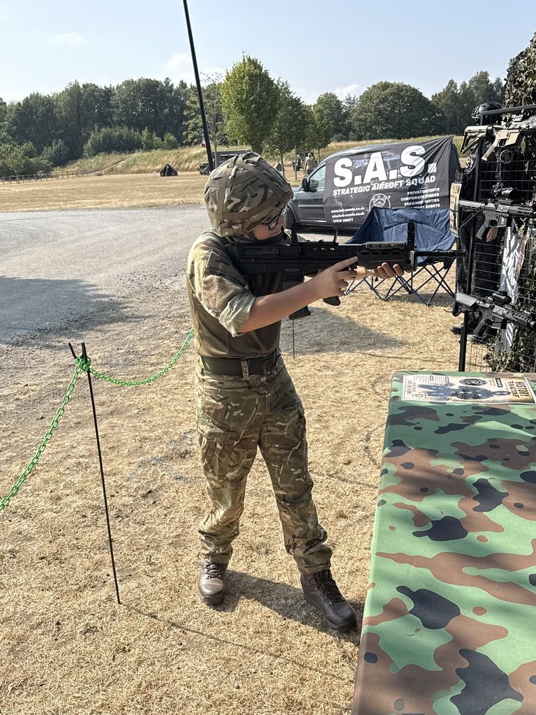 An S.A.S. range marshal in camouflage taking aim beside the range banner