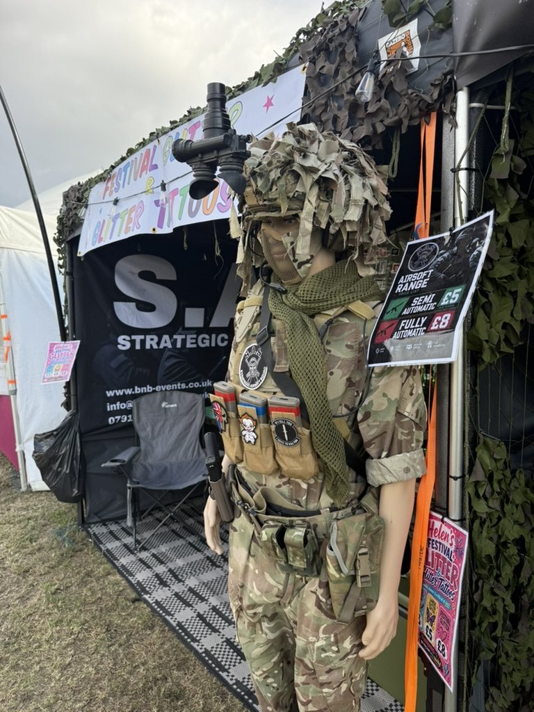 An S.A.S. range marshal in full kit beside the camouflaged range at a military show