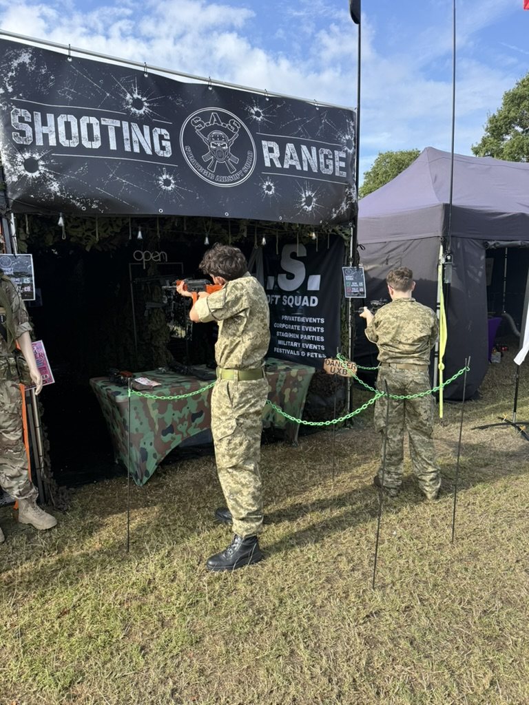 Two colleagues taking turns on the airsoft range under the S.A.S. shooting range banner
